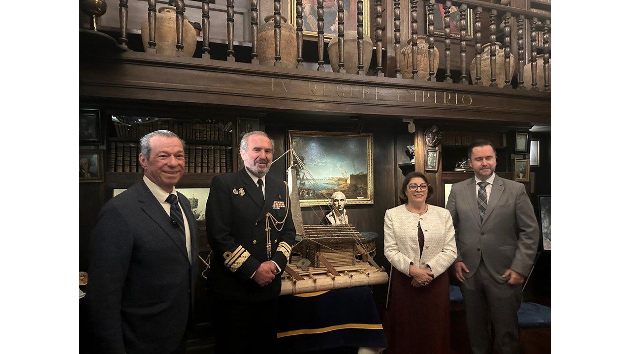 El autor con un oficial de la Armada y otros invitados ante una maqueta de balsa en una biblioteca histórica