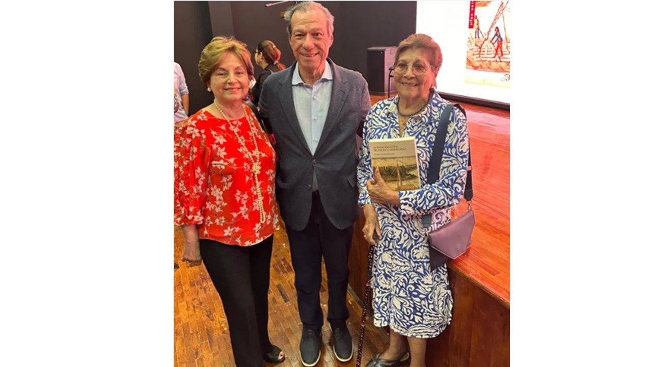 Benjamín Rosales con dos asistentes que sostienen el libro en el auditorio de la ULEAM