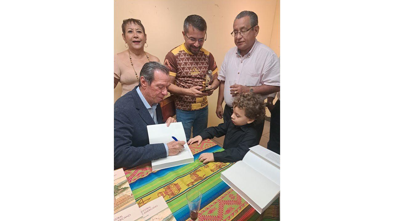 El autor firma un libro rodeado de lectores, entre ellos un niño, en Portoviejo